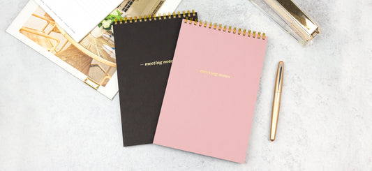 Two meeting note pads on a marble tabletop