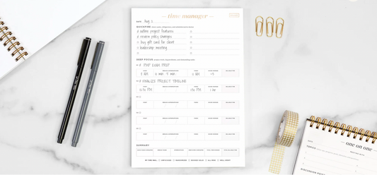 A time manager pad with two pens on a white marble countertop