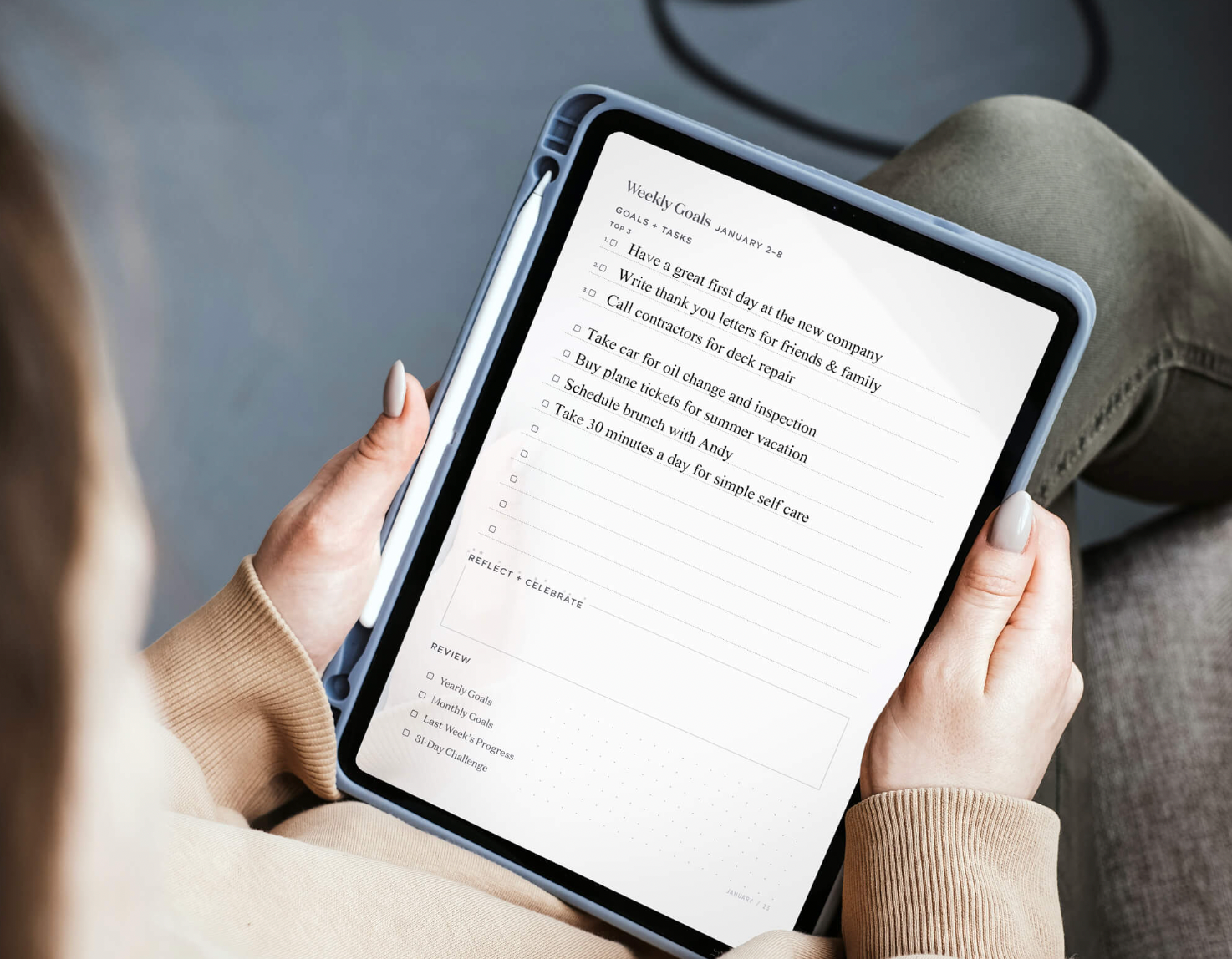 A woman holds an ipad with a weekly task list on it