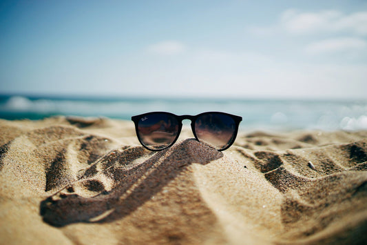 sunglasses on a beach in front of an ocean