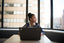 A woman working at a laptop looks out a window