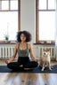 A woman does morning exercises and meditates on a yoga mat next to a small dog.