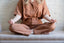 A woman in a meditation pose on a white bench