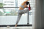 A woman stretches on her balcony next to a cup of coffee