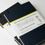 Stack of notebooks with visible branding and text on a light background