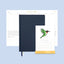Navy blue planner with a stand featuring a calendar and illustration of a bird on a light blue background