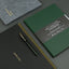 Green notebook with pen on a dark surface