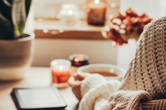 A cozy table with a candle, a book, and a cup of tea