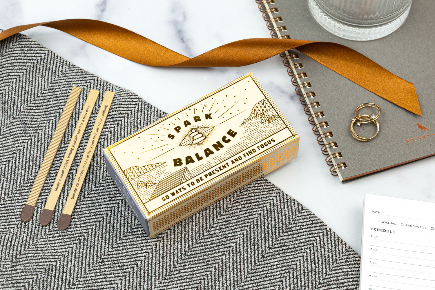 A spark balance gift set on a marble tabletop with a tan colored ribbon