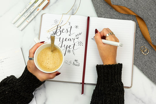 A planner with the words "best year yet" and a person's hands holding a mug of coffee