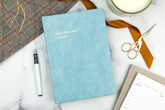 A planner sits open to a calendar page on a gold silky sheet.