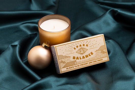 candle, christmas ornament, and spark balance box on green satin