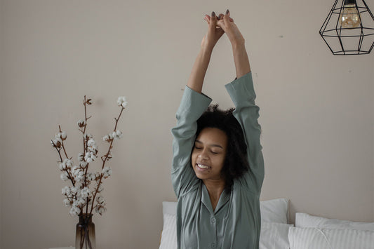 A woman stretching her arms and smiling in bed