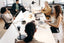A group of five people sitting around a white meeting table.
