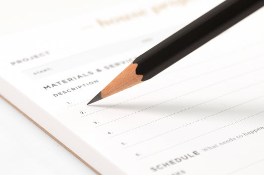 A black pencil writing on a white notepad