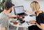 Two people at a table look at a laptop together.