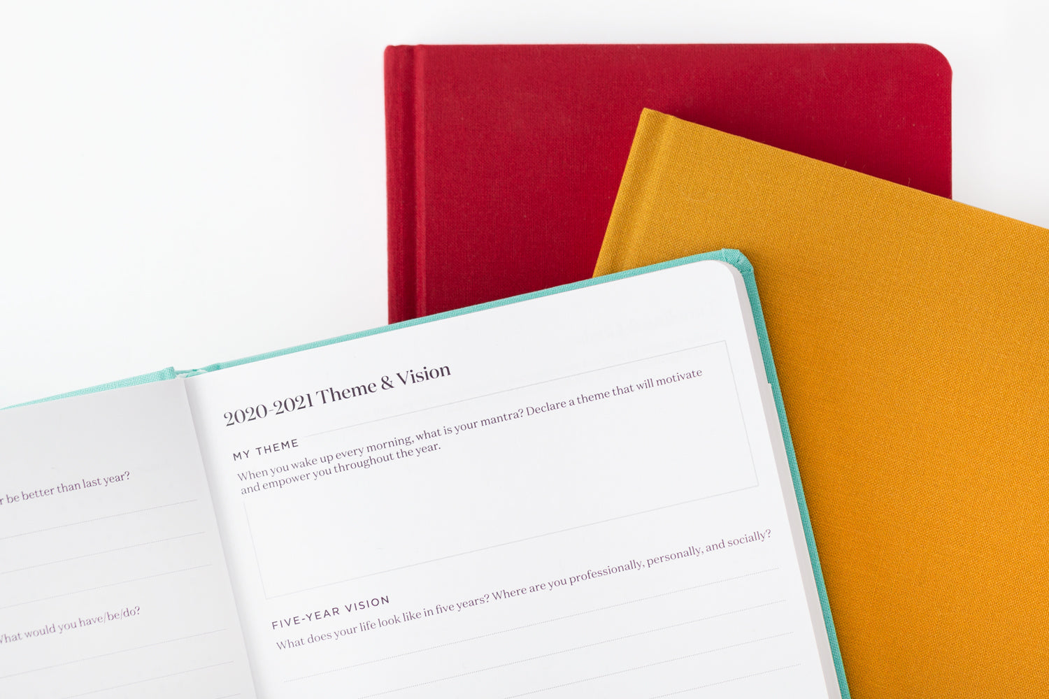 A colorful stack of planners - one teal, one red, and one goldenrod.