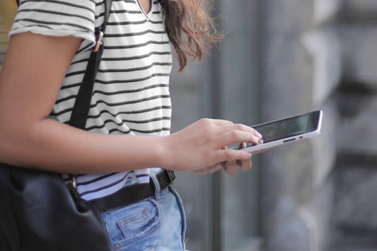 woman in striped shirt looks down at her phone