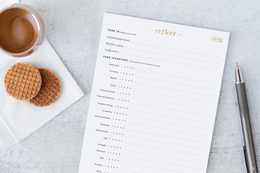 A cozy setup for checking in on life balance: a cup of tea, cookies, and a self-reflection pad.