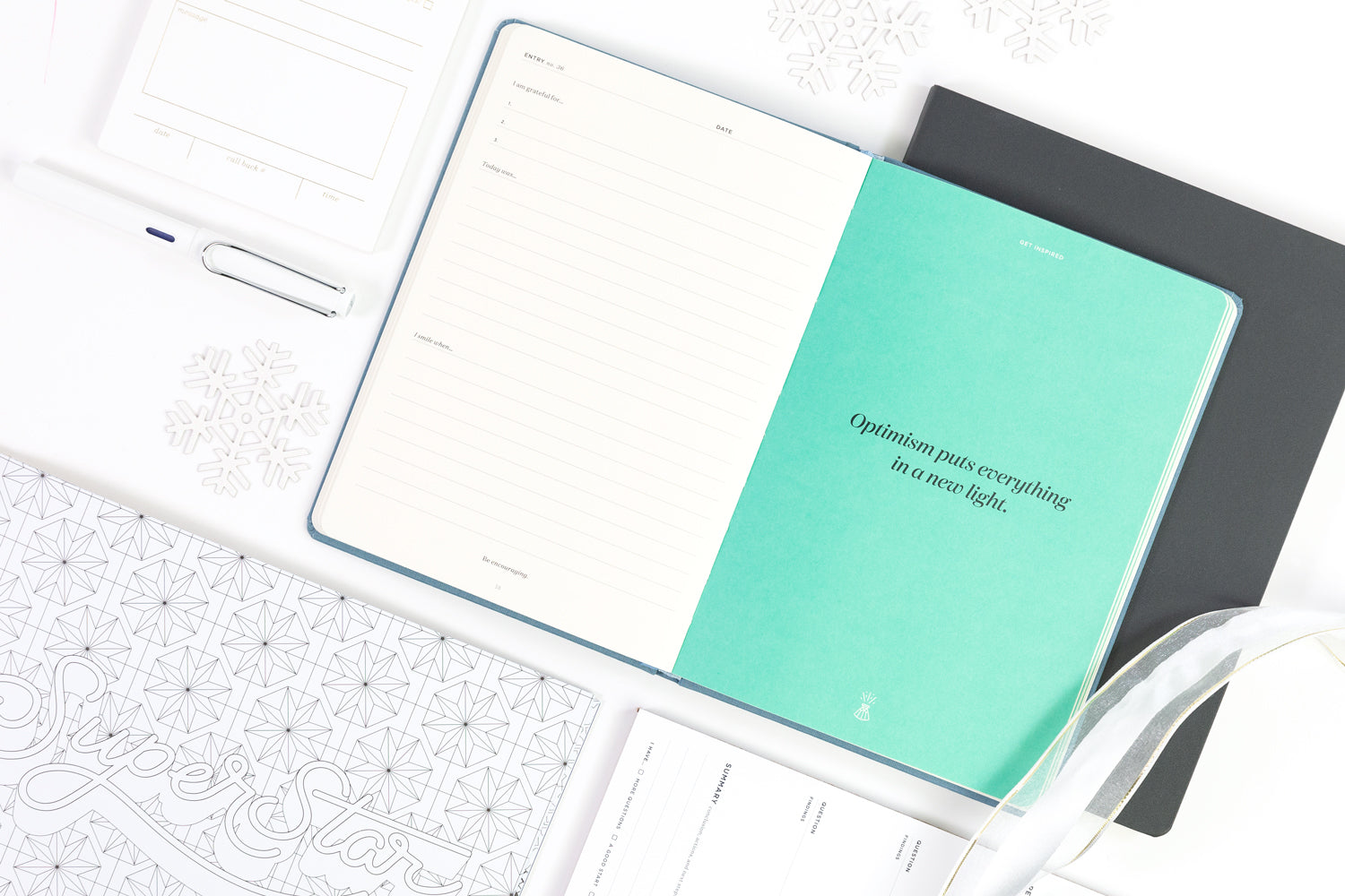 Creative gifts on a white background: a gratitude journal, executive notebook, and a coloring book.