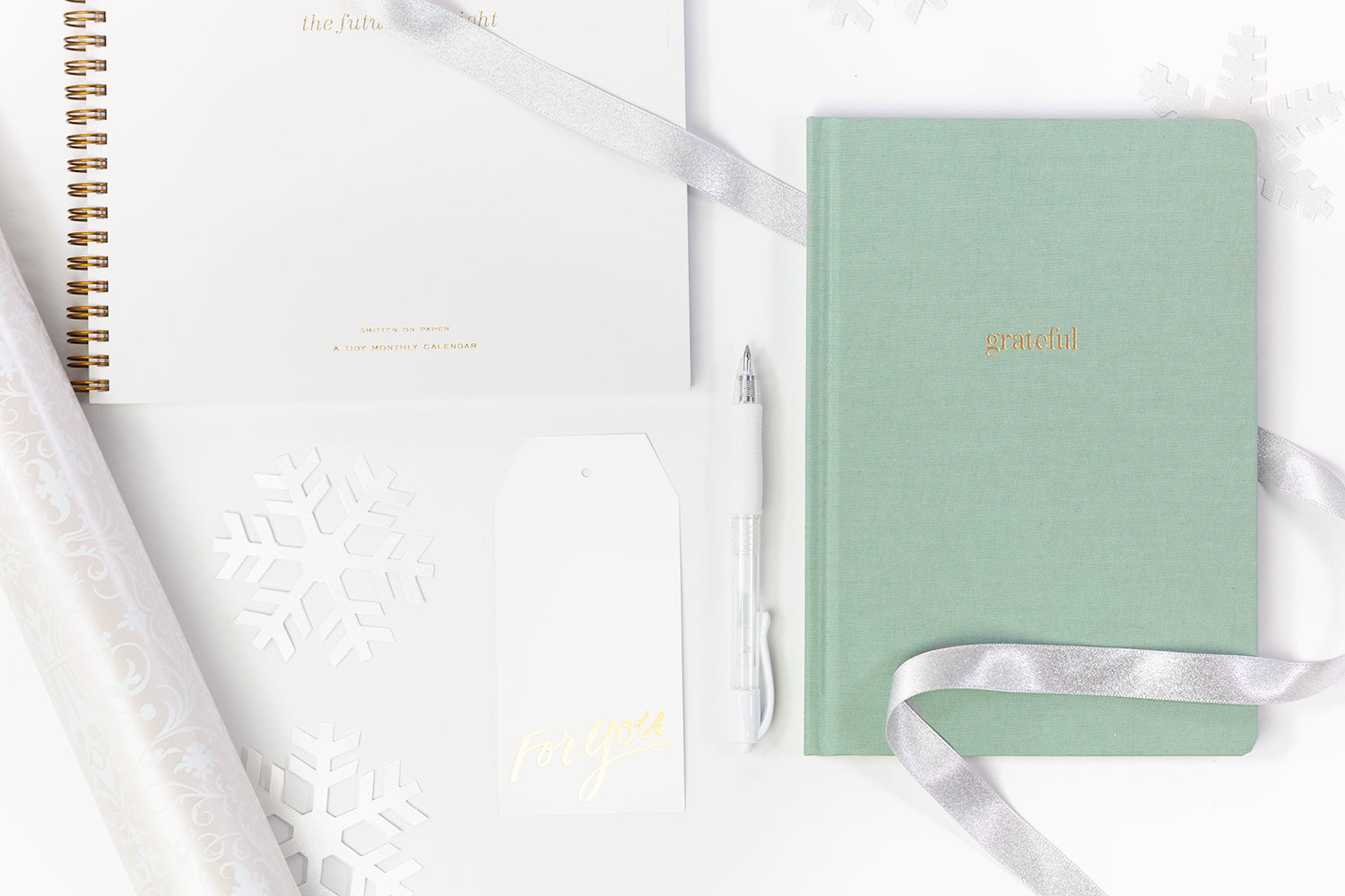 An array of inexpensive gifts for coworkers including a notebook, planner, and pen.