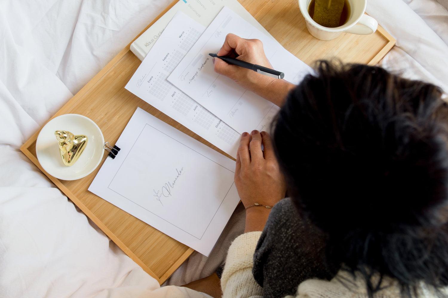 woman sitting on a bed writing on paper