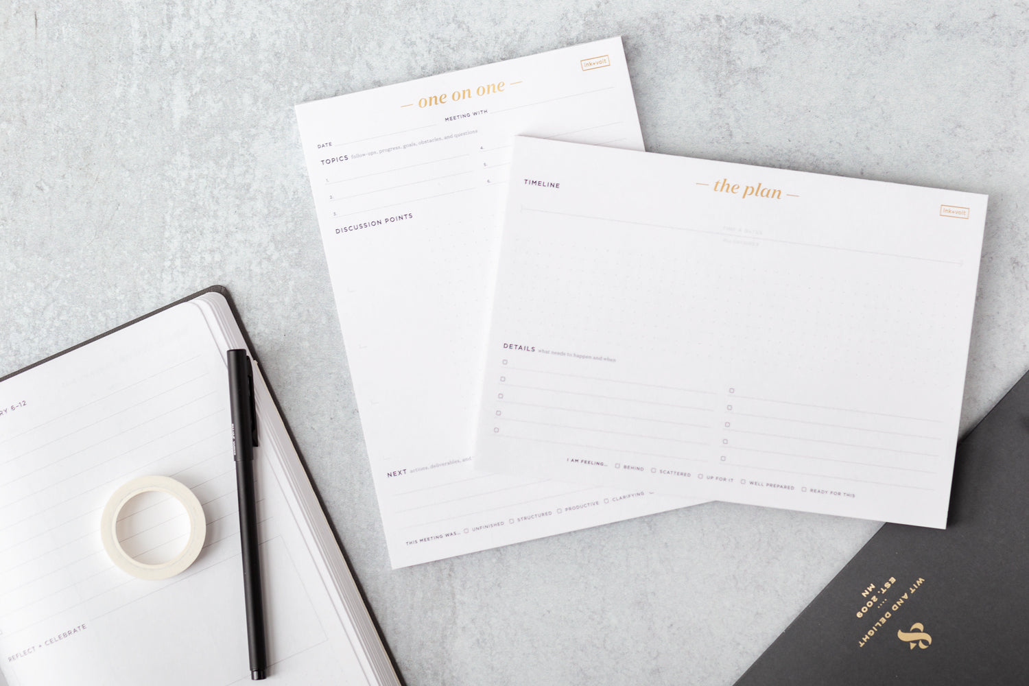 A one-on-one pad and a planning pad sit on a table next to an executive planner and pen.
