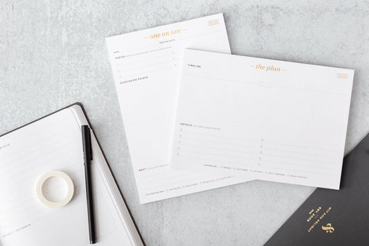 A one-on-one pad and a planning pad sit on a table next to an executive planner and pen.