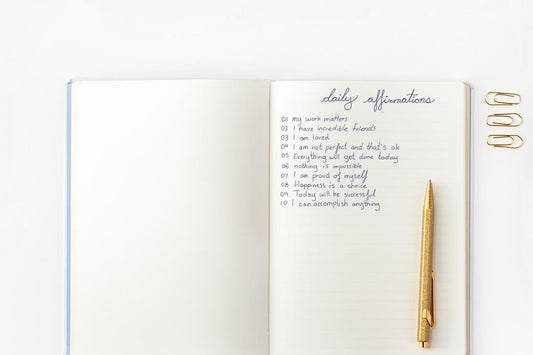 A notebook is open to a page of handwritten daily affirmations.