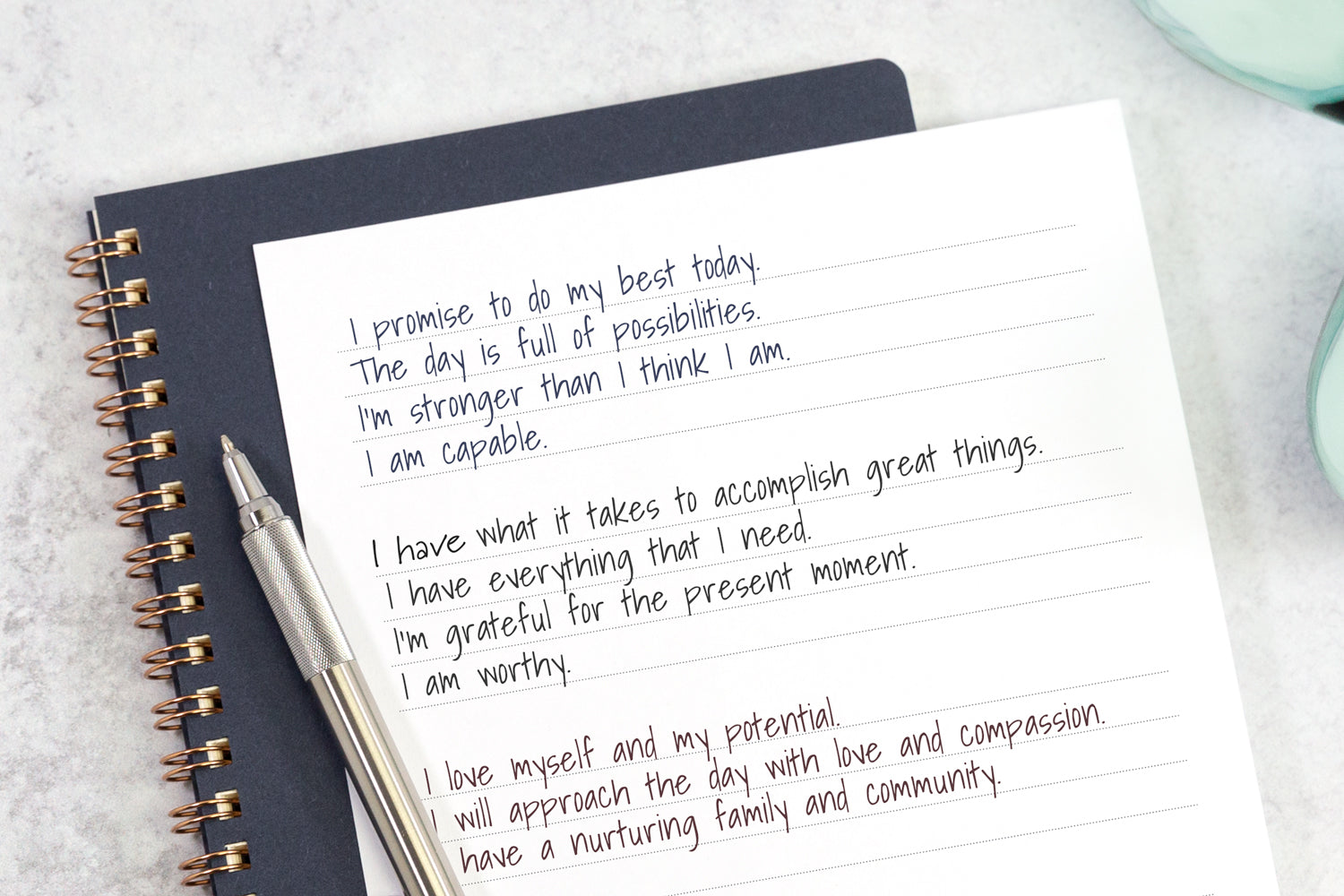 A hand-written list of morning affirmations on white notebook paper.