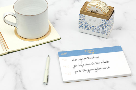 A cup of tea next to a morning to-do list on a white countertop