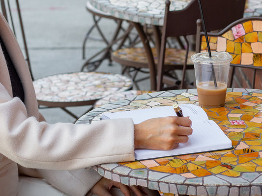 woman sitting at a table writing in a planner