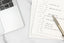 A self-reflection notepad next to a computer on a white table