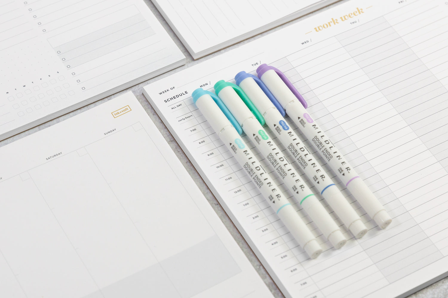 An array of productivity notepads with a set of pastel highlighters laid on top.
