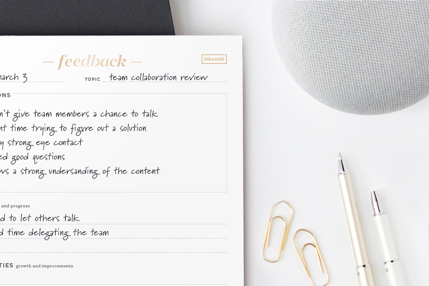 A feedback notepad on a white desk next to gold paperclips and white pens