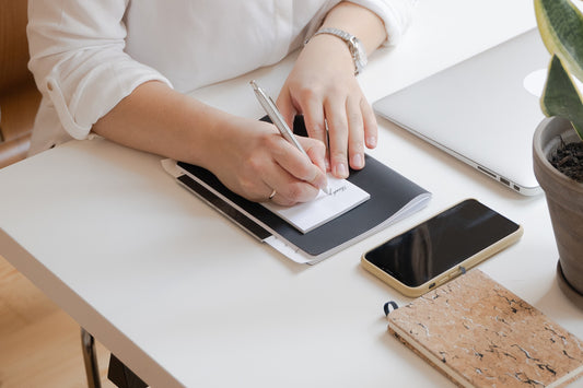 person writing thank you note while sitting at a desk