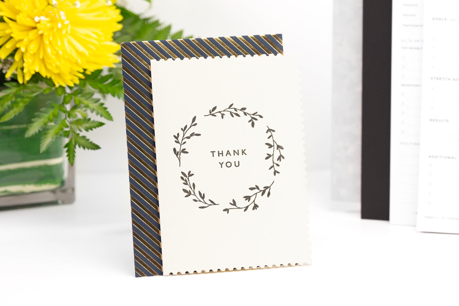 An assortment of items like flowers, string, and cookies around a greeting card that reads "thank you"