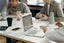 A laptop on a meeting table with people around it