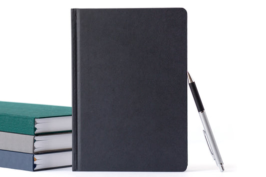 A stack of planners and a pen on a white background