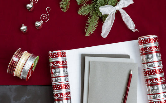 a stack of notebooks and a pen are ready to be wrapped as a gift