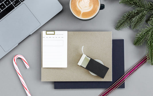 Ink+Volt products on a desk with a ribbon, coffee, evergreen bough, and a candy cane