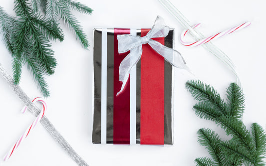 A wrapped gift sits on a white table, surrounded by evergreen boughs and candy canes