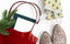 A red bag with a planner and productivity pad, next to a sprig of spruce, glittery shoes, and a gift.