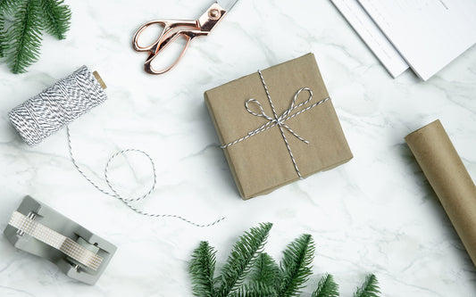 A package wrapped in brown paper sits on a desk with wrapping materials