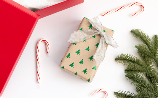 A small gift sits wrapped on a table surrounded by candy canes