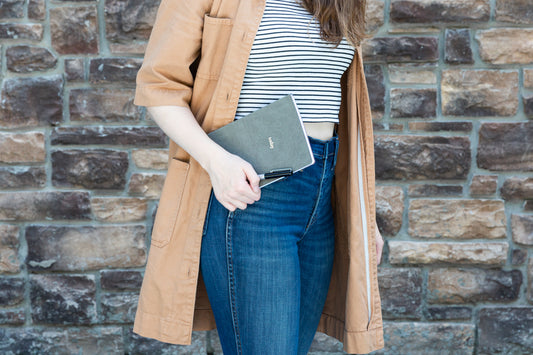 a woman standing in front of a stone wall with a today daily planner