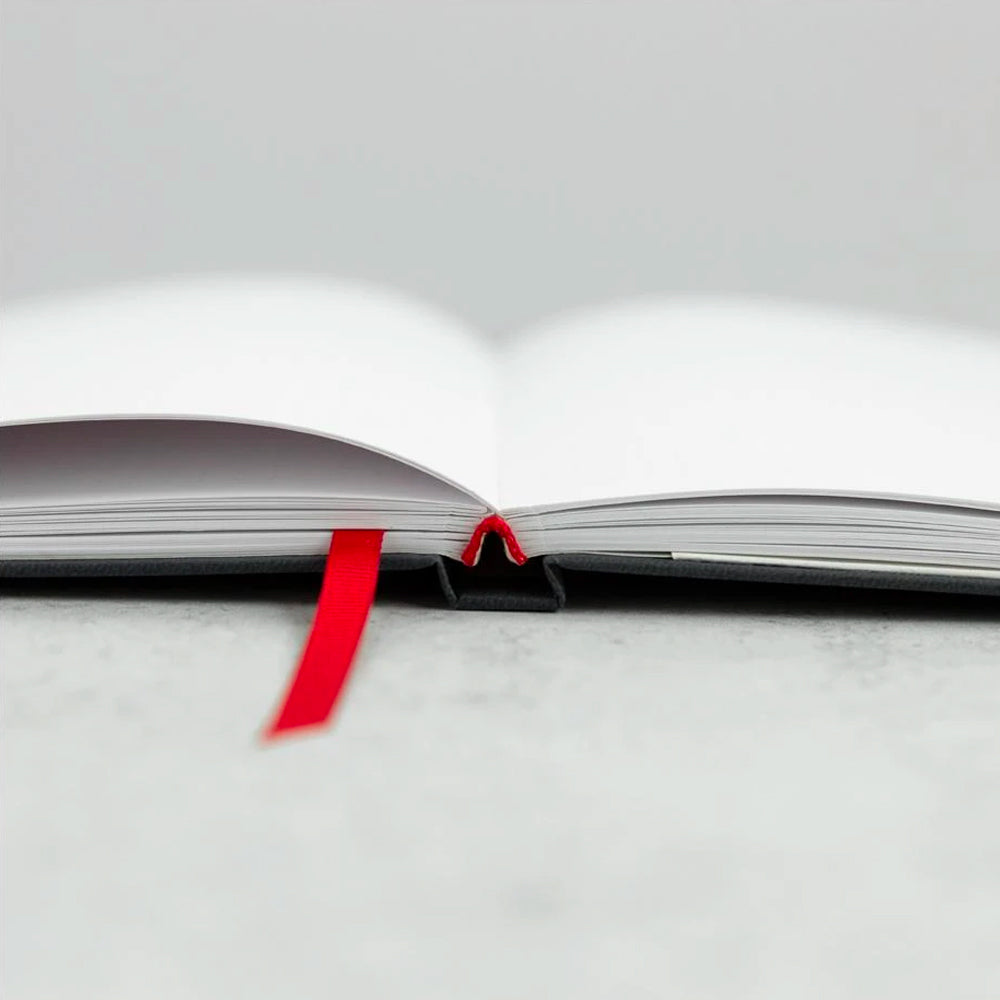 A planner with a red ribbon open to a blank page