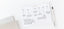 An ink+volt project planing timeline pad sits on a white desk next to a pen, filled out with important project dates.