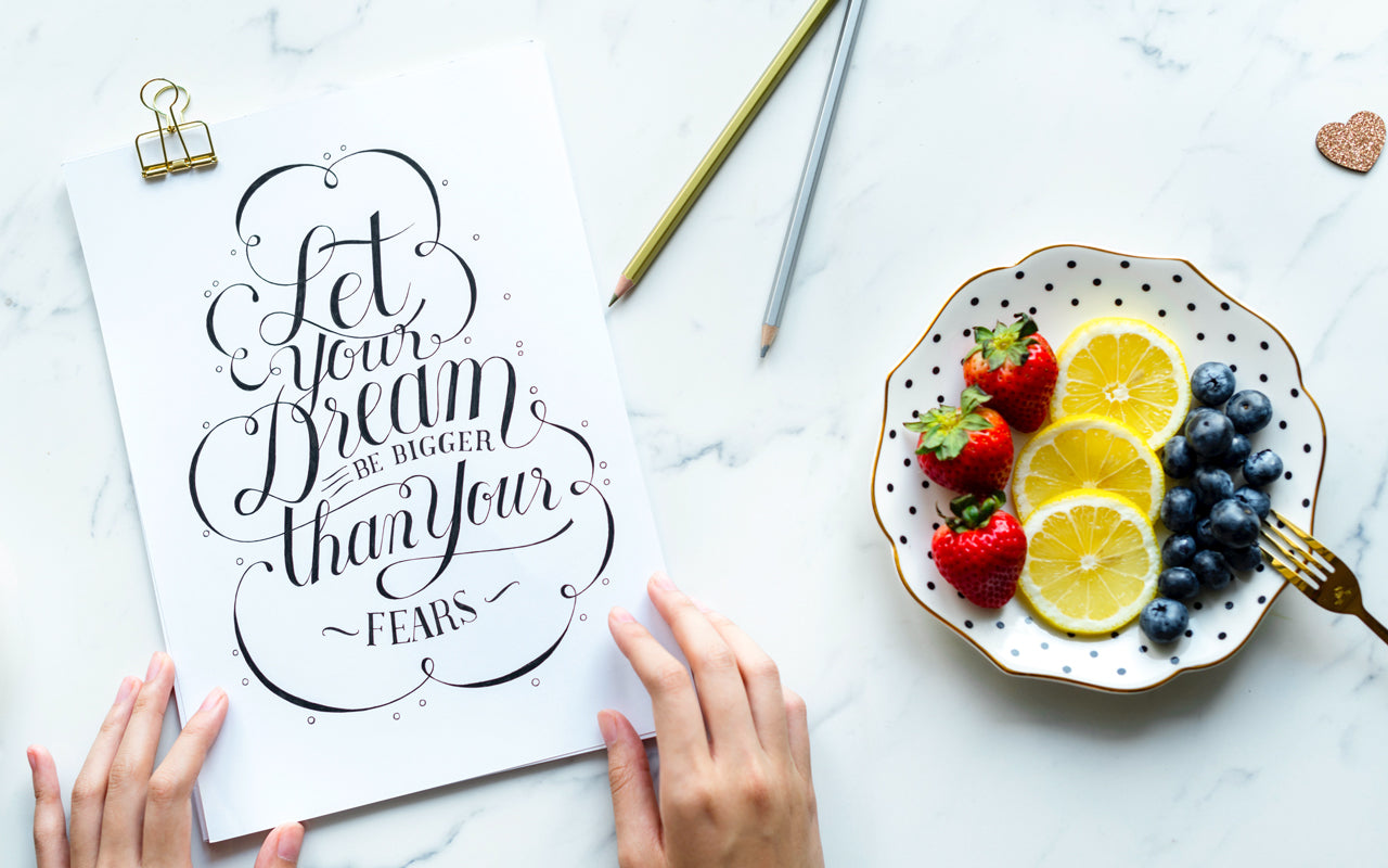 A plate of fruit sits on a marble counter next to a hand-written card that says "let your dream be bigger than your fears".