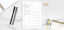 A time manager pad with two pens on a white marble countertop